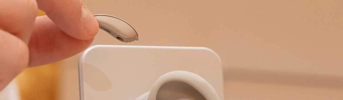 Mano che posiziona un apparecchio acustico su un modello di orecchio