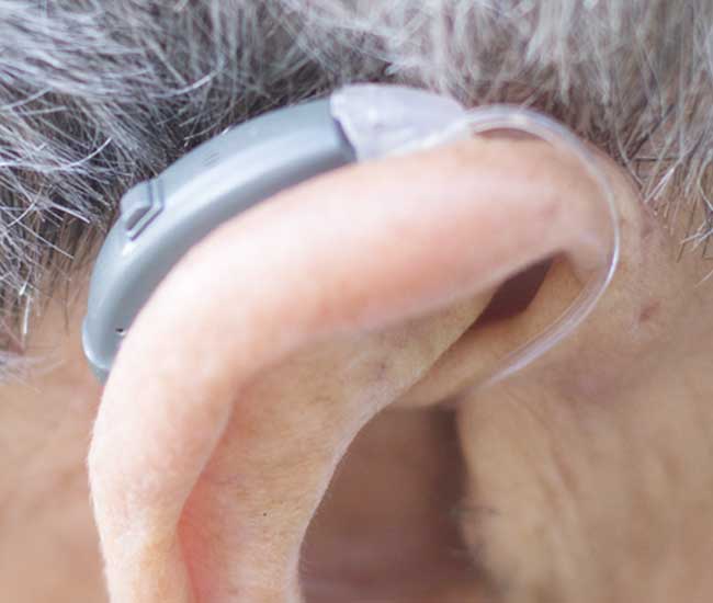 Primo piano di un apparecchio acustico BTE (Behind-The-Ear) con tubicino trasparente